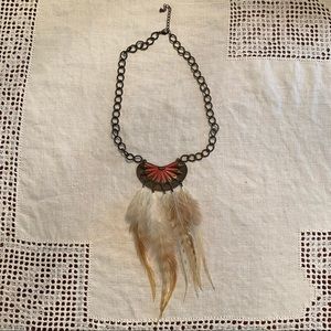 Feather pendant necklace with pink tone design.